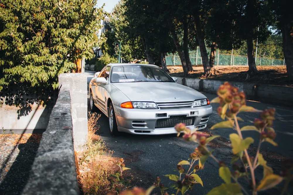 Silver Nissan Skyline R32 GT-R parked on a tree-lined street